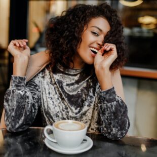 Portrait of happy carefree black woman enjoying coffee break in Paris.
